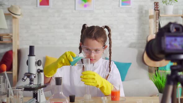 Girl Teen Blogger in a White Coat and Glasses in the Laboratory