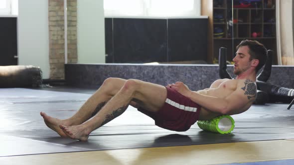 Athletic Muscular Man Relaxing After Training, Using Foam Roller