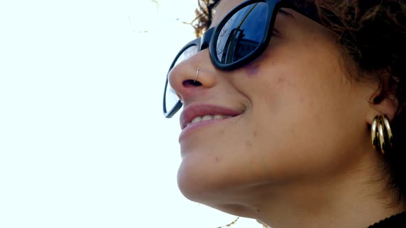 happy woman wearing sunglasses smiling in the reflected light of the sun