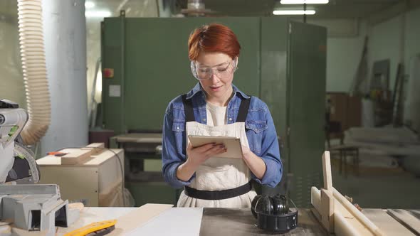 Cute Caucasian Female Carpenter Using Digital Tablet Working On Design Project