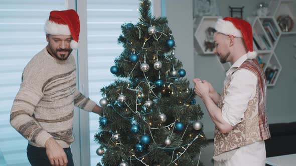 Gay Male Couple at Home Hanging Decorations on Christmas Tree Together