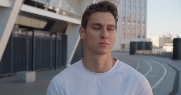 Portrait of a Confident Sporty Man Looking at the Camera in the Morning at the Stadium