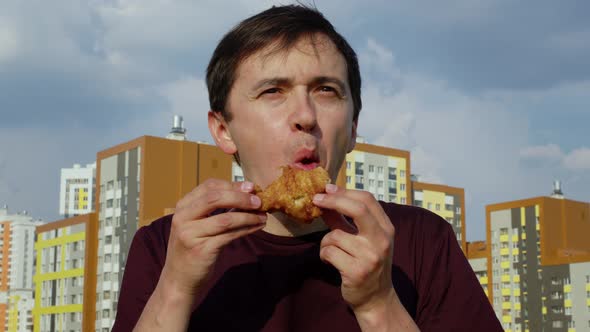 A Man Eating Fat Fried Chicken with Great Appetite