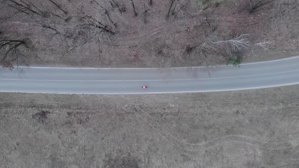 Isolated bike riding. Athlete rides fast and pedals intensively on empty car road in forest. 