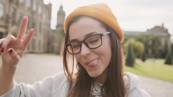 Happy Cheerful Young Woman Showing Tongue Giving Wink on City Street