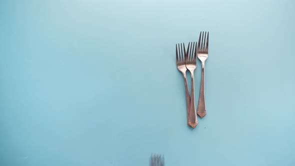 Putting Cutlery Fork with Knife and Spoon on Blue Background