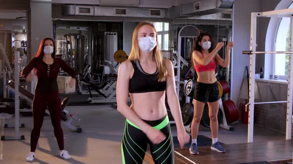 Group of Three Girls in Protective Masks Stretching Before Workout in the Gym. The Concept of