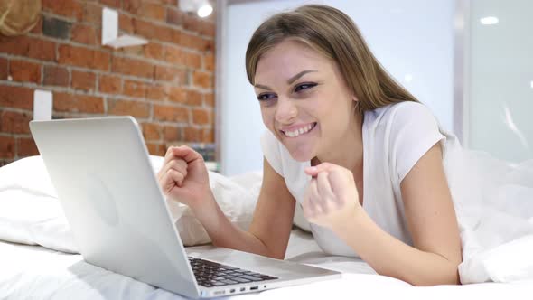 Young Woman in Bed Working on Laptop and Reacting to Success