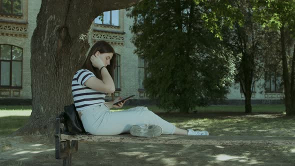 Lovely Girl Networking with Tablet Pc on the Bench