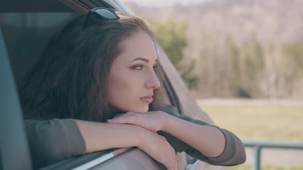 Concentrated Lady with Brown Hair Looks Out of Car Window