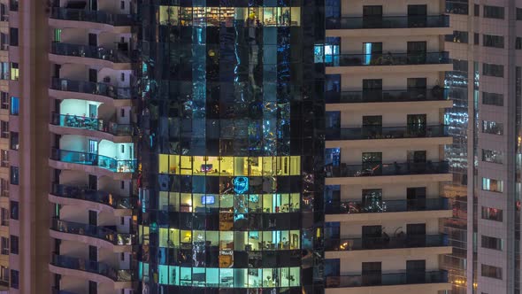 Windows of the Multistorey Building of Glass and Steel Lighting Inside and Moving People Within