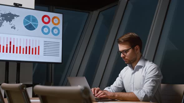 Young businessman in shirt typing letters on laptop