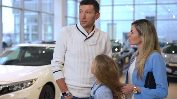 Unsure Caucasian Man Choosing New Car in Dealership with Family Talking Looking Around
