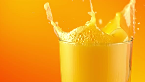 Super Slow Motion Shot of Ice Cubes Falling Into Glass of Orange Juice and Making Splash at 1000Fps alt
