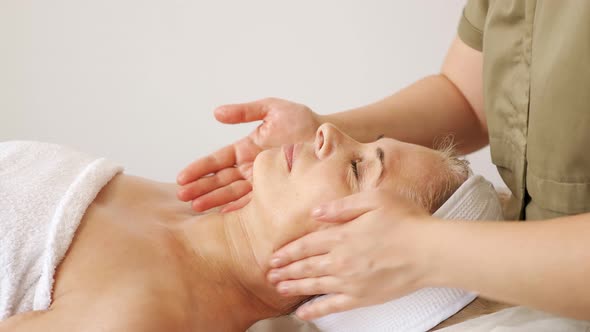 Specialist Makes a Face and Neck Massage to a Woman in a Beauty Salon