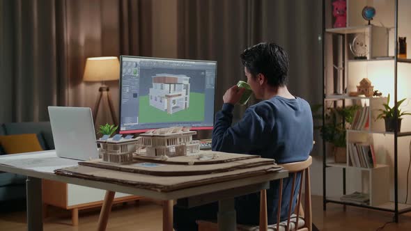 Asian Male Engineer Drinking Coffee While Designing House On A Desktop At Home
