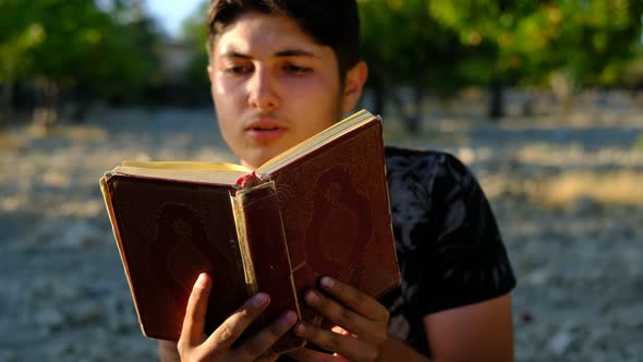 Young Man Reading Quran Outdoors