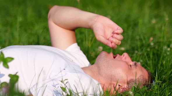 A Young Guy Eats a Berry While Resting on the Grass