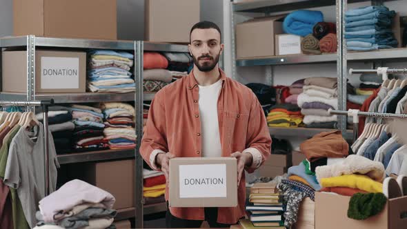 Portrait View of the Caucasian Volunteer Man Holding Cupboard Box with Donation Word and Looking at