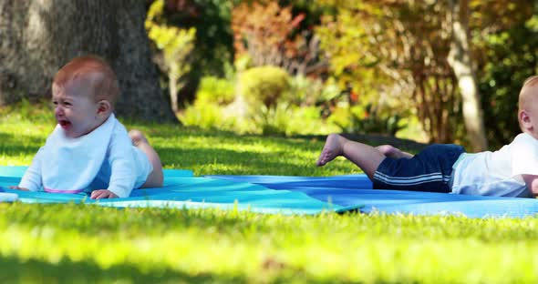 Two babies lying on exercise mat