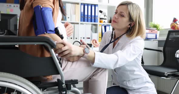 Doctor Listens with Stethoscope to Belly of Pregnant Woman in Wheelchair