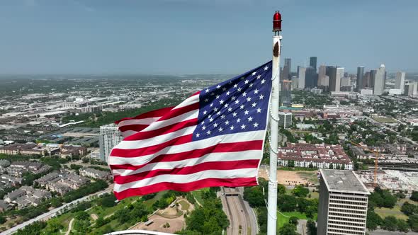 Houston Texas skyline. American flag proudly waves above cityscape. Aerial orbit. City in USA.