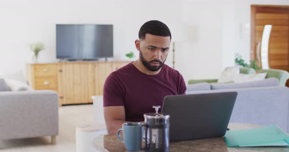 Man talking on smartphone while using laptop at home