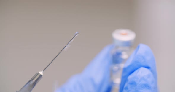 Extreme Close Up of Hand Holding Syringe and Vaccine in Hand in Laboratory.