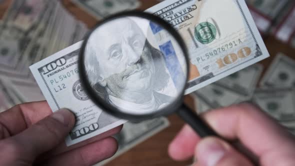 One Hundred Dollars Inspecting Under Magnifying Glass on Money Background