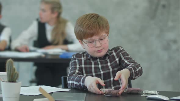 Happy Little Boy at the Table Counts Money