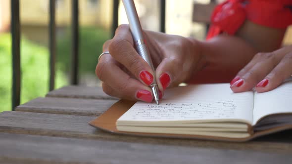 Close-up of a woman writing in a journal diary traveling in a luxury resort town in Italy, Europe.
