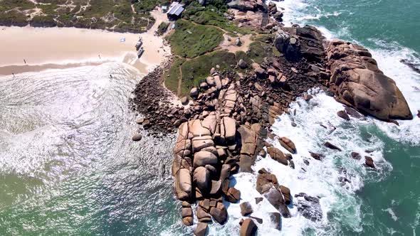 Aerial drone view of tropical tourist beach with rocks touching the sea and sand in Florianópolis ma