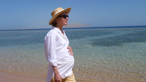 Young Pregnant Woman Walking At Sea Beach