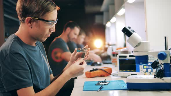 Male Specialist is Observing Circuits of a Mobile Phone