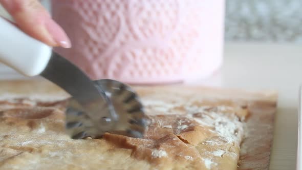 A Woman Cuts A Baked Cake Base. The Woman's Hands And Knife Are Visible. Close Up Shot