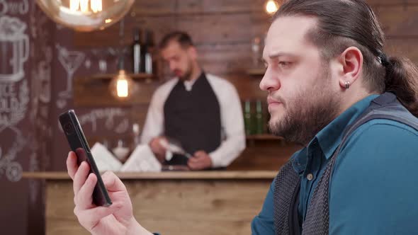 Handsome Man with Long Hair Scrolling the Smartphone