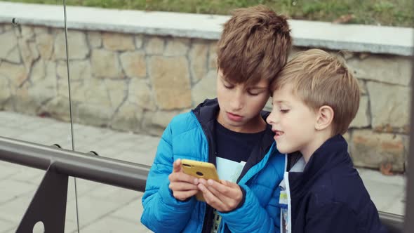 Two Boys Are Sitting At The Bus Stop.