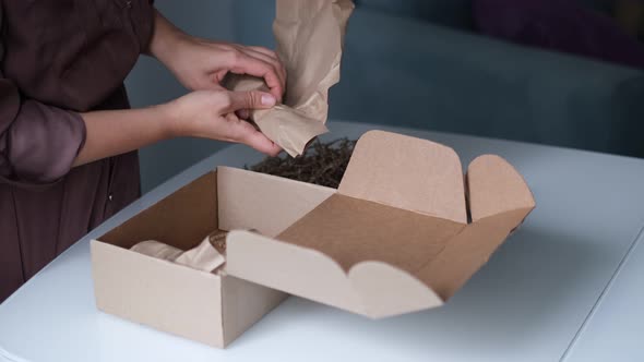 Woman is Packing Jars of Cosmetics in a Box to Send a Parcel Through a Delivery Service