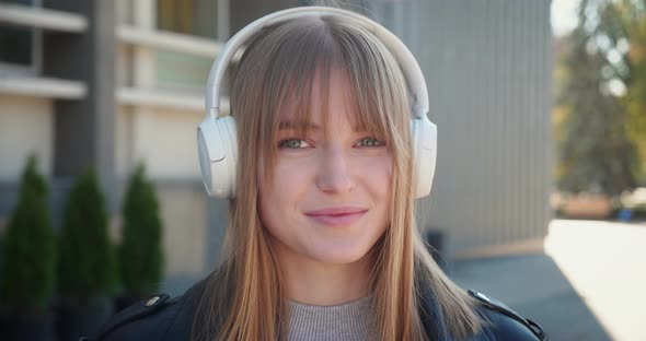 Young Woman in Short Hair with Headphone Looking in Camera Shot of Young Woman's Hair Blowing in