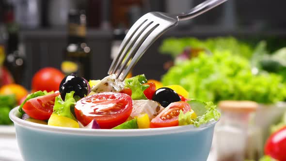 Greek salad on fork, fresh vegetable salad served with healthy food ingredients