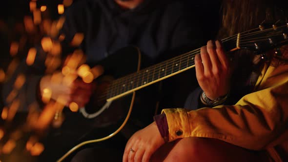 Playing guitar at a campfire