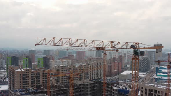 Yellow Tower Crane at Work at the Height of a Large Construction Site Against the Background of