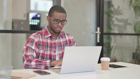 African Man Working on Laptop in Office