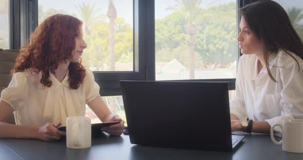 Businesswomen colleagues discuss a project using a computer at workplace