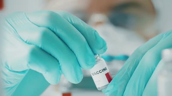 Scientist Examines a Vial with the Vaccine