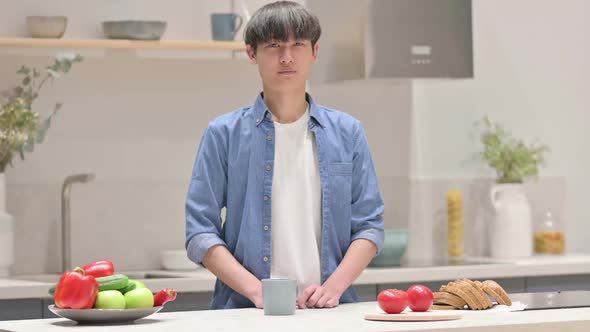 Asian Man Looking at the Camera While Standing in Kitchen