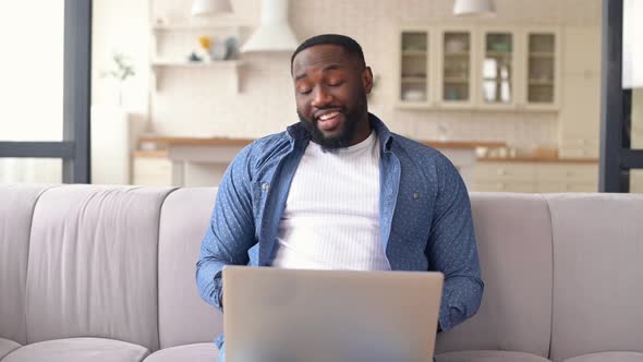 Happy African Man Using a Laptop for Video Call at Home