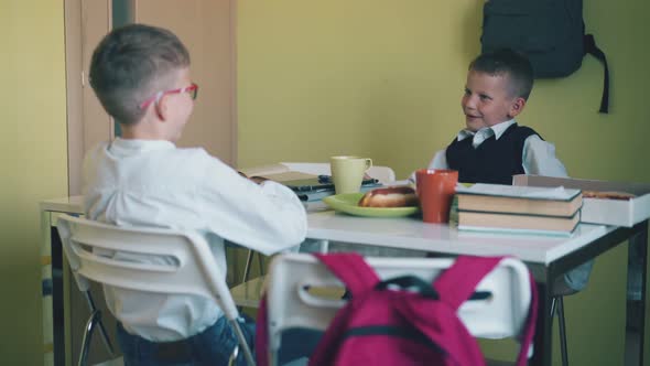 Schoolboys Have Dinner at Table with Textbooks in Canteen