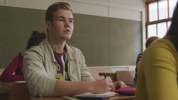 Caucasian boy raising his hand in class