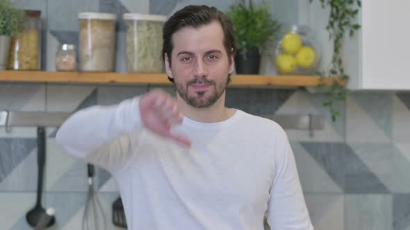 Young Man Showing Thumbs Down in Kitchen